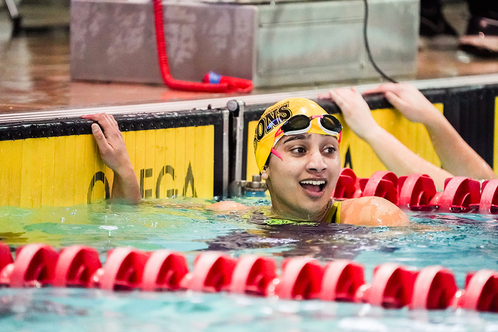 Young female swimmer touching the wall at the pool’s edge