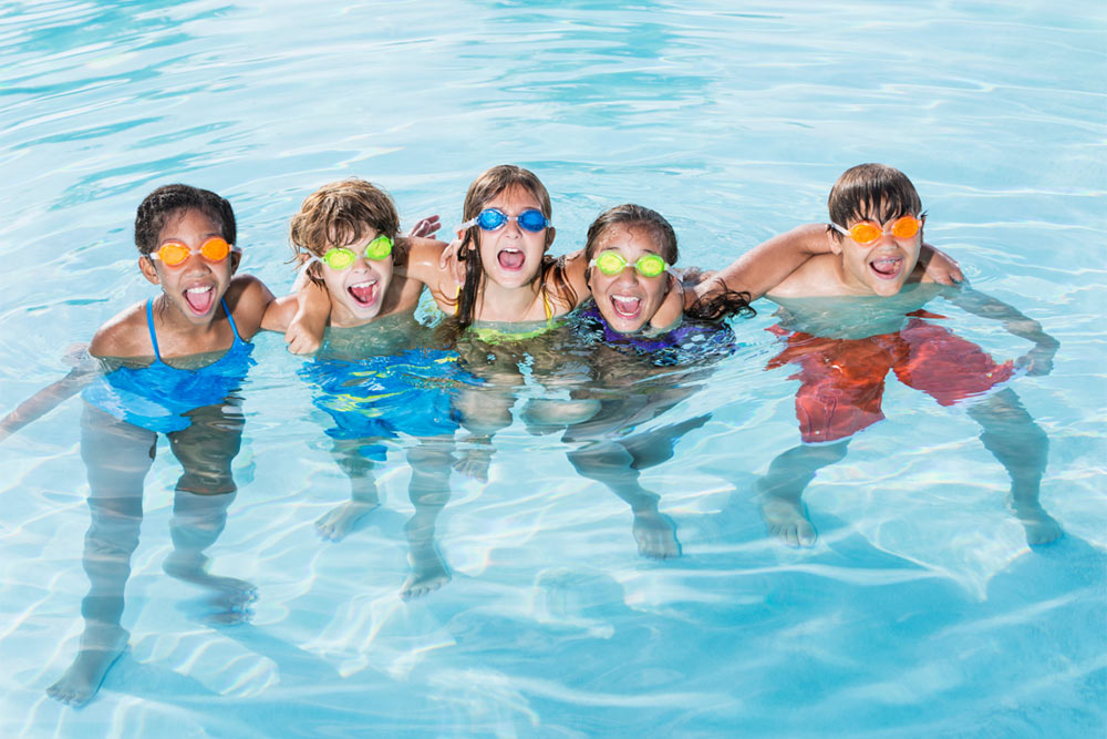 kids standing together smiling in swimming pool