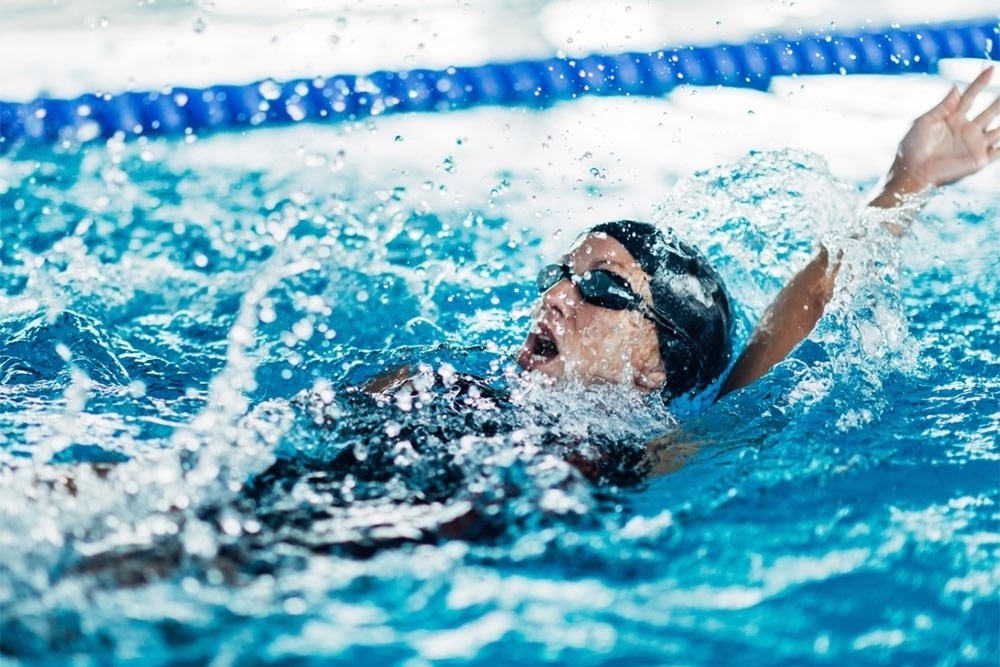 female swimming backstroke in indoor swimming pool